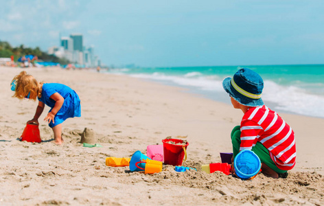 小男孩和女孩玩沙子中，在夏天的海滩上