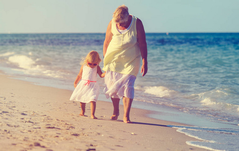 快乐奶奶和小孙女走在海滩