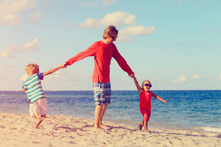 父亲带儿子和女儿在海滩玩照片