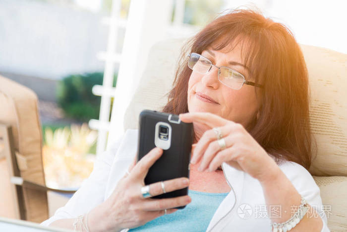 有吸引力的中年女人用她的智能手机