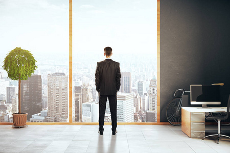 电脑工作背影周到的商人于现代办公的城市全景,空白笔记本和装饰植物