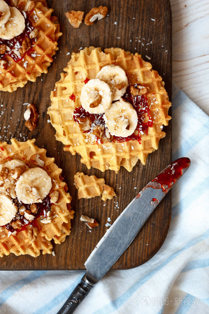 堆栈比利时华夫饼配核桃果酱和一根香蕉黑木制背景上甜甜的食品的概念