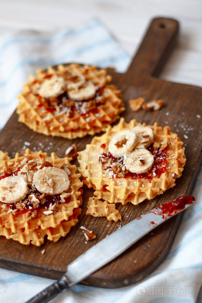堆栈比利时华夫饼配核桃果酱和一根香蕉黑木制背景上甜甜的食品的概念
