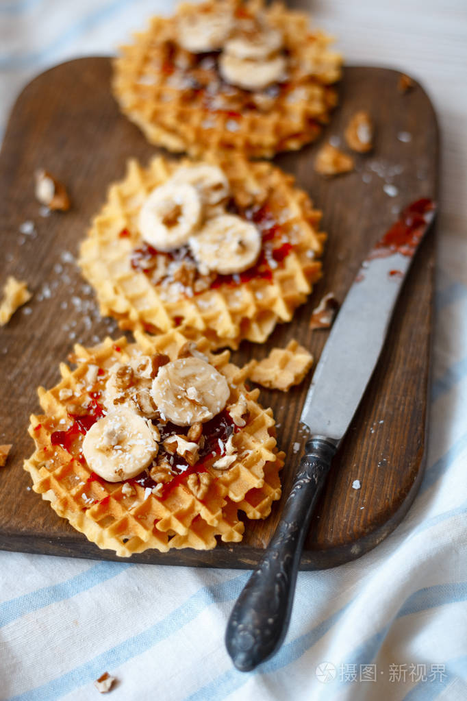 堆栈比利时华夫饼配核桃果酱和一根香蕉黑木制背景上甜甜的食品的概念