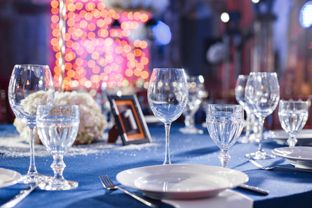 婚礼。宴会。椅子和桌子的客人，配餐具和陶器和蓝色的桌布盖着