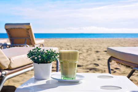 在海滩的拿铁咖啡。冰咖啡星冰乐或在高大的玻璃。海视图背景西班牙巴塞罗那
