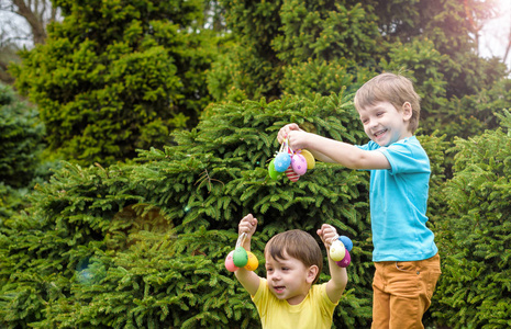在盛开的复活节彩蛋上的孩子们春天花园。儿童寻找彩蛋花草甸。蹒跚学步的男孩和他弟弟的朋友的孩子玩户外