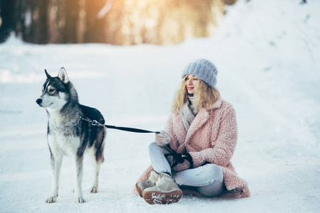 赫斯基狗在白雪皑皑的森林里的漂亮女孩
