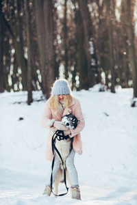 赫斯基狗在白雪皑皑的森林里的漂亮女孩