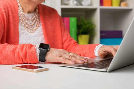现代老年妇女在办公室用笔记本电脑工作