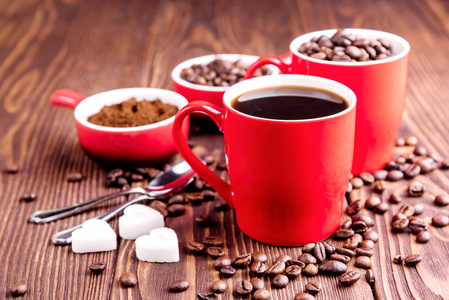 两杯咖啡杯，咖啡豆木制背景周围红色杯子的咖啡豆