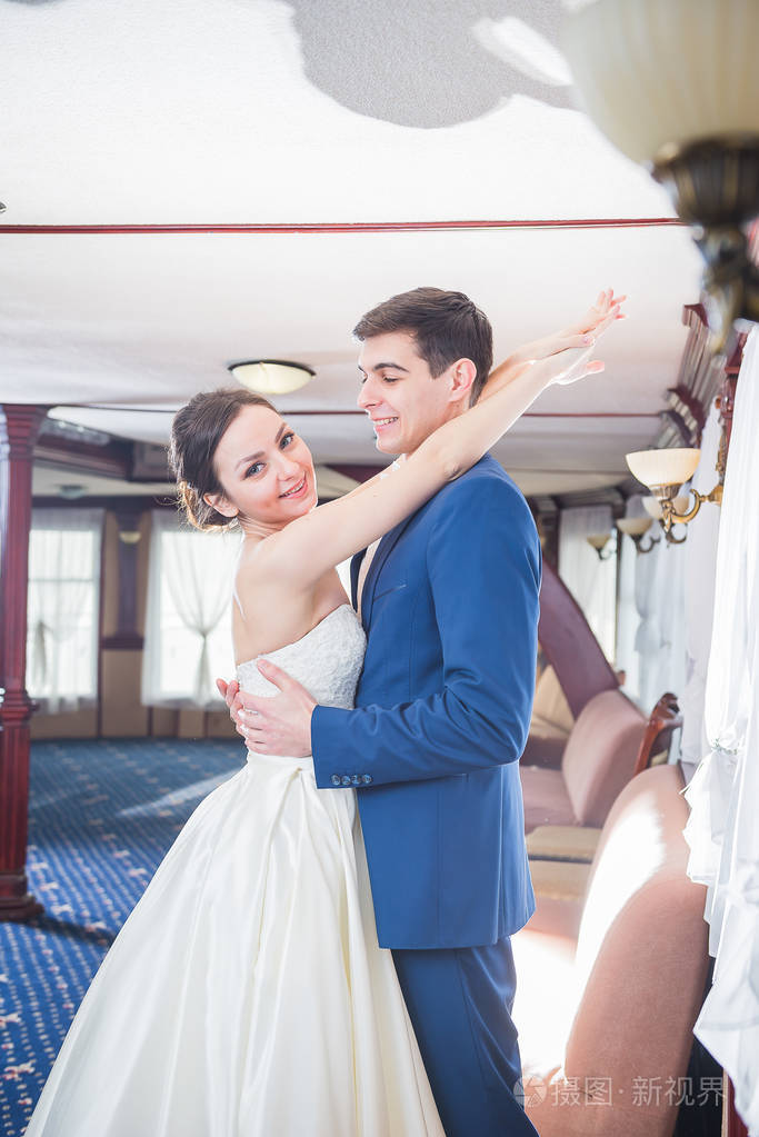 新娘穿白色婚纱的样子笑的很开心.新郎在一个蓝色的服装.寻找到彼此.