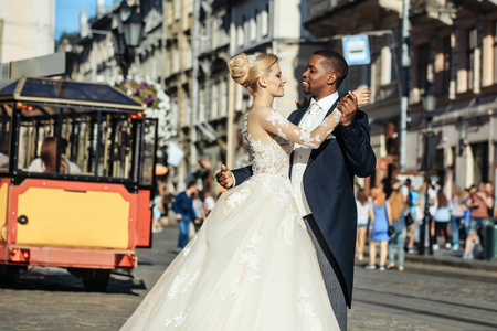 快乐的非洲裔美国新郎和可爱的新娘，在街道上跳舞