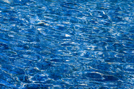 the blue water swimming pool with sun reflections照片