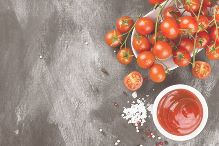 番茄酱在白碗 香料和樱桃西红柿上一个黑色的背景。顶视图，复制空间。食品背景。色调