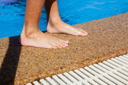 赤脚站在游泳池边的孩子照片