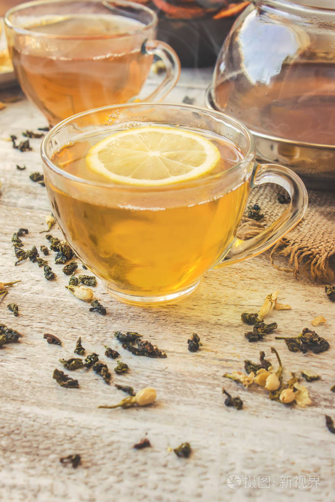 绿茶与茉莉花和黑色透明柠檬在明亮的背景上一小杯茶壶选择性的焦点
