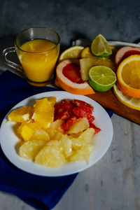 各种各样的柑橘水果切成切片橙 柚 柠檬 葡萄柚 石灰一杯橙汁。铺在木板和天然木材纹理的背景上的老式白板