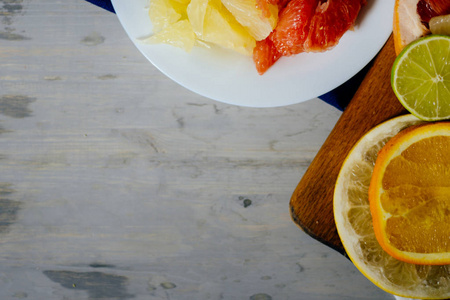 各种各样的柑橘水果切成切片橙 柚 柠檬 葡萄柚 石灰一杯橙汁。铺在木板和天然木材纹理的背景上的老式白板