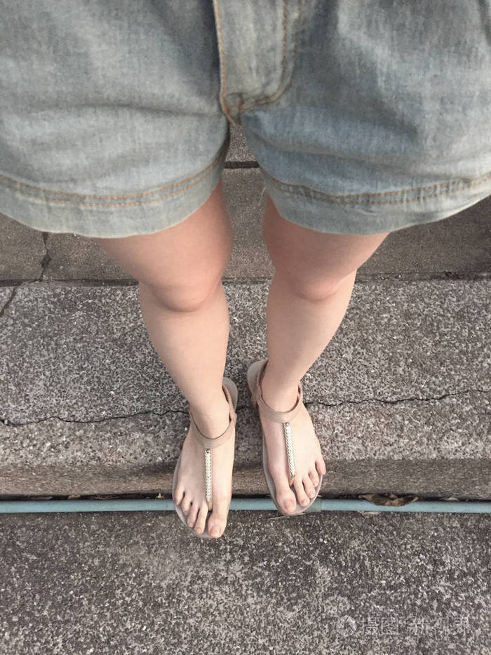 在楼梯背景的黄金凉鞋年轻女孩腿