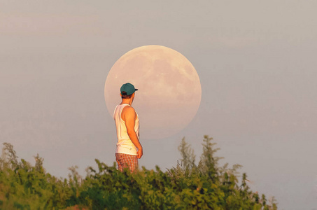人类看着一个巨大的满月在地平线上升起
