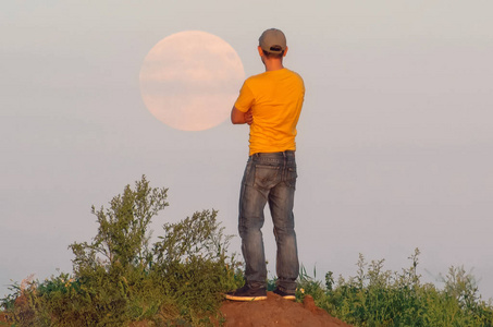 一个人望着天边升起的大圆月图片
