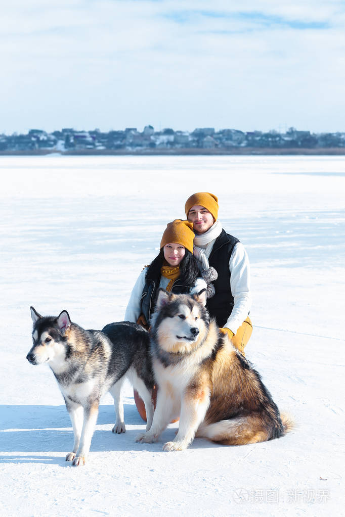 与狗微笑和拥抱冬天对年轻夫妇的肖像