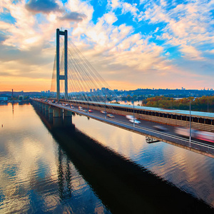 汽车和铁路桥梁在乌克兰首都基辅。在第聂伯河河日落桥。背景下的一个美丽的黄昏在基辅的基辅桥。在黄昏的阳光桥
