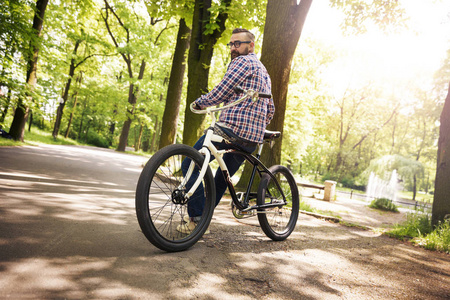 现代年轻人坐在自行车在公园看后面