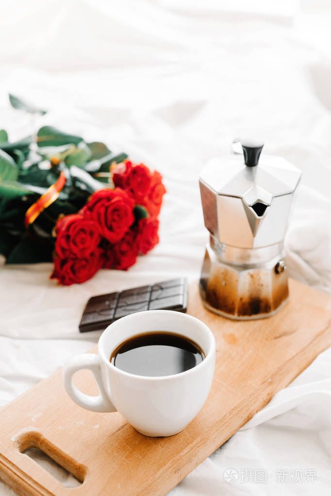 一杯咖啡,咖啡在木板上,一束红玫瑰在白色背景上