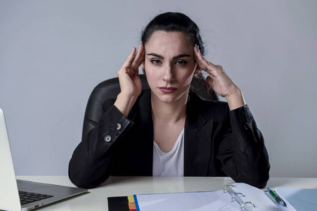 笔记本电脑上遭受剧烈头痛偏头痛的应力在办公室工作的女商人