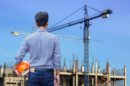 拿着黄色的安全帽,在建筑施工现场的工程师照片