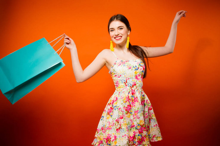 购物袋快乐微笑的年轻女子的画像。橙色背景
