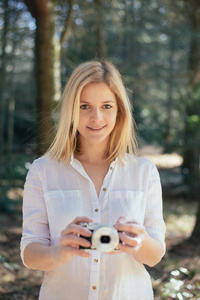 金发女孩抱着一个复古相机，年轻的女人是一位摄影师用老式的相机，户外和阳光，肖像，复制空间