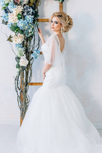 新娘站在白墙背景与花在她的手图片