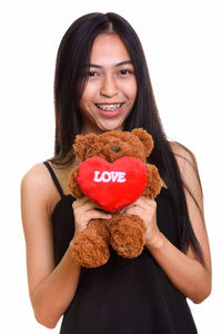 年轻快乐亚洲少女微笑着拿着玩具熊