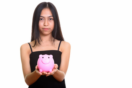 工作室拍摄的年轻亚洲少女抱着存钱罐