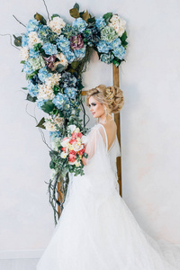 新娘站在白墙背景与花在她的手
