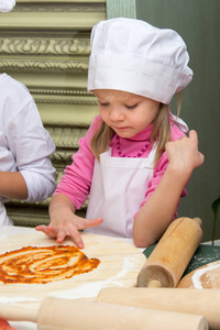 厨师的帽子的小女孩烹饪比萨饼