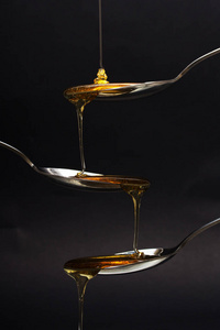 蜂蜜倒从深色的背景衬托的勺子