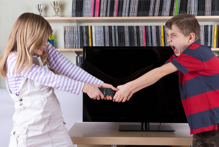 兄弟姐妹争夺遥控器在电视机前图片