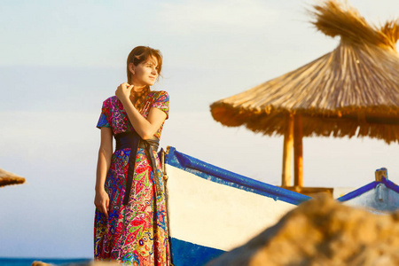 长多彩的服饰，独自站在船边的海滩在日落时分的吸引力黑发