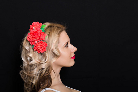 金发女郎铺设和镶边的红色的花，在深色背景上的女人