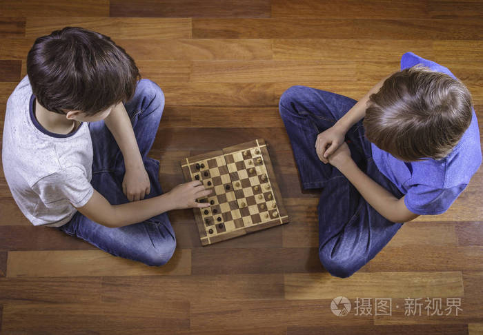 孩子们坐在木地板上下棋顶视图游戏教育生活方式休闲概念