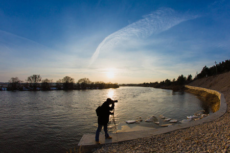 专业摄影师拍照在日落时洪水河