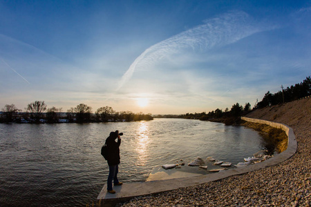 专业摄影师拍照在日落时洪水河
