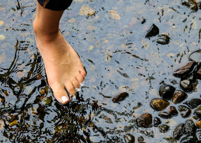 岩石旁的水中女孩的脚