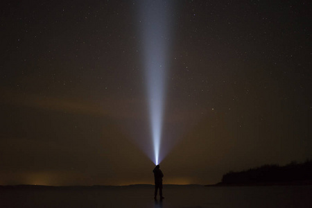 人类站在冰湖在冬季景观。在与手电筒夜空中星星闪耀起来。斯堪的那维亚欧洲瑞典