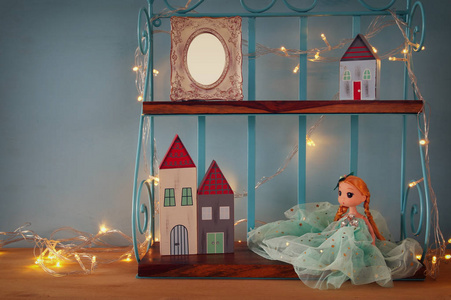 可爱的玩具娃娃 空白的相框和温暖花环灯旁边的小木屋