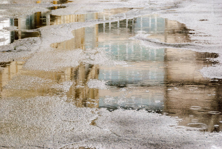 雨淋时在城市街道上的水坑倒影照片